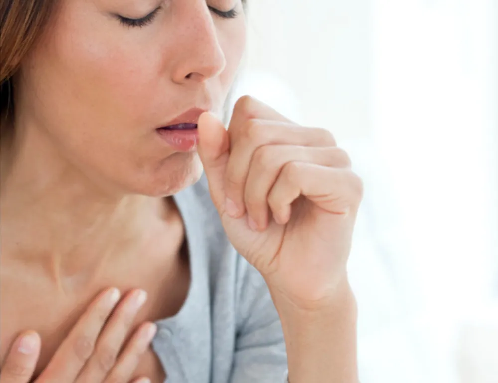 Person holding their chest and coughing, indicating respiratory discomfort which can be associated with severe arthritis or related conditions